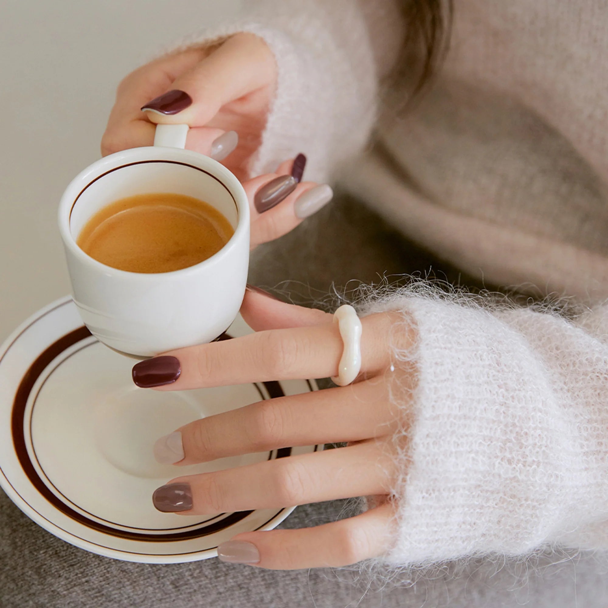 Espresso fincanı tutan elde kahverengi ve mocha tonlarında jel tırnak