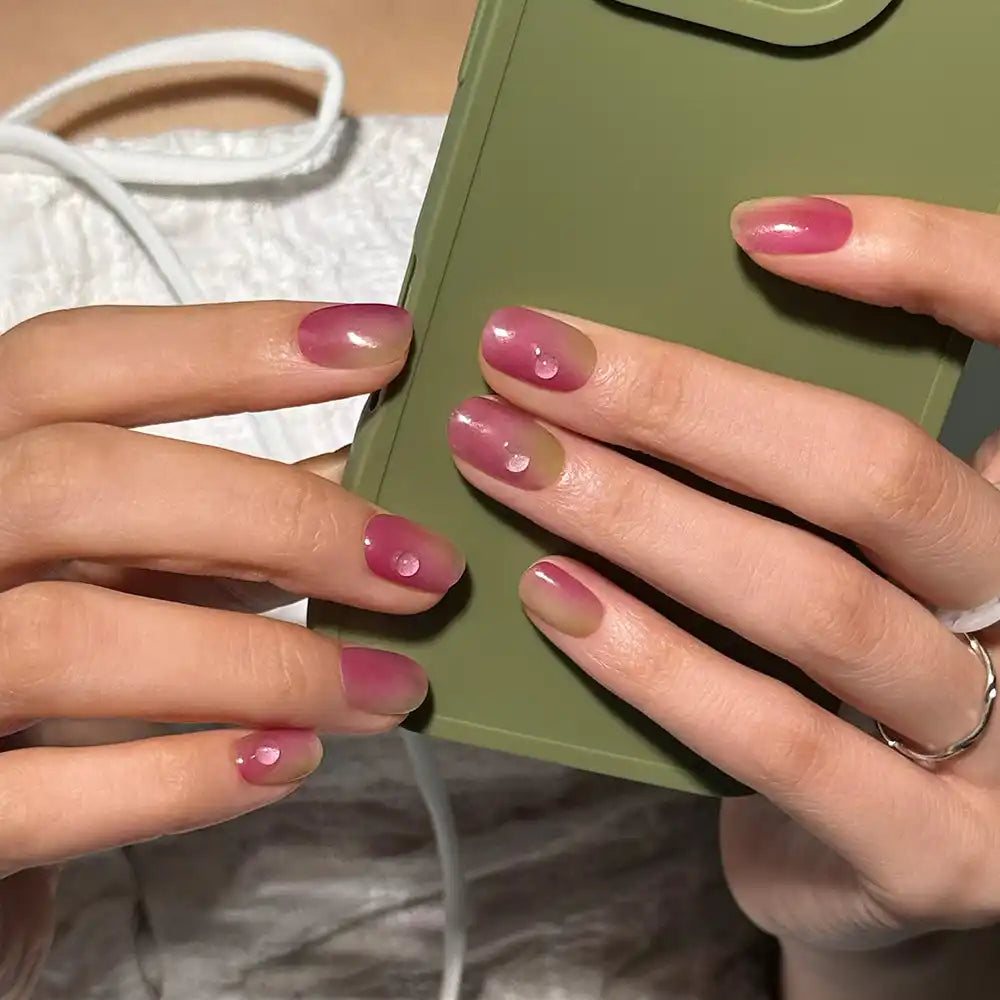 Ombré pembe ve nude tırnaklara sahip eller, bazı tırnaklarda şeffaf 3D damla detayları bulunuyor.